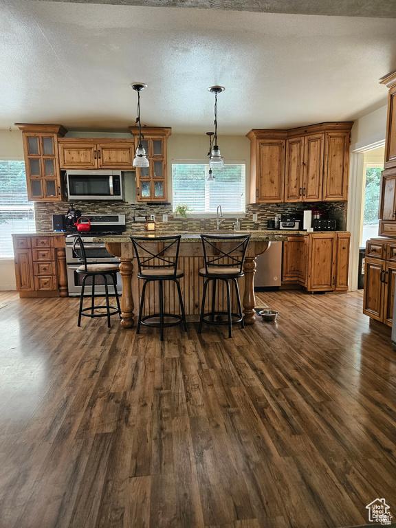 223 N 2520 W, Provo, UT 84601 - kitchen featuring dark wood finished floors, tasteful backsplash, brown cabinetry, and appliances with stainless steel finishes