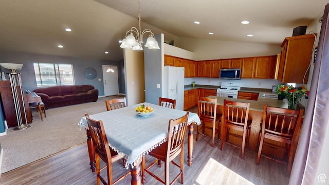 dining area featuring light wood finished floors, lofted ceiling, recessed lighting, and an inviting chandelier