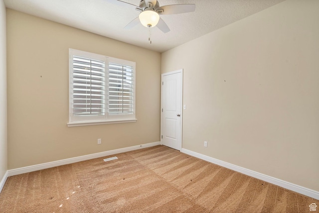 carpeted spare room featuring baseboards, a textured ceiling, ceiling fan, and visible vents