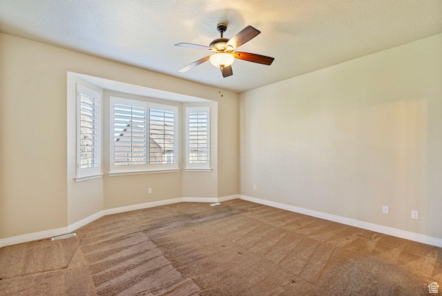 carpeted spare room with visible vents, a textured ceiling, baseboards, and ceiling fan