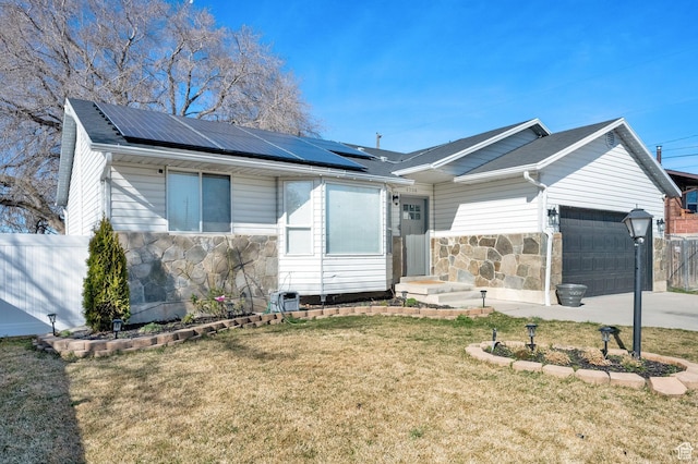 view of front of property with stone siding, a front lawn, a garage, and roof mounted solar panels