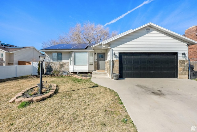 single story home featuring an attached garage, a front lawn, fence, and roof mounted solar panels