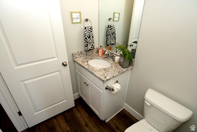 bathroom featuring toilet, baseboards, wood finished floors, and vanity