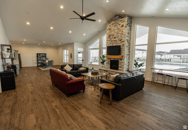 living area with wood finished floors, a stone fireplace, ceiling fan, high vaulted ceiling, and recessed lighting