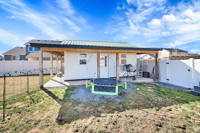 2466 W 3375 S, West Haven, UT 84401 - rear view of house featuring metal roof, a patio, a fenced backyard, a trampoline, and a gate