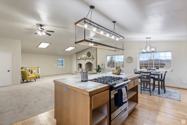 kitchen with tile counters, stainless steel gas range oven, open shelves, a wealth of natural light, and vaulted ceiling