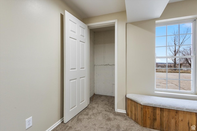 hallway featuring carpet flooring and baseboards