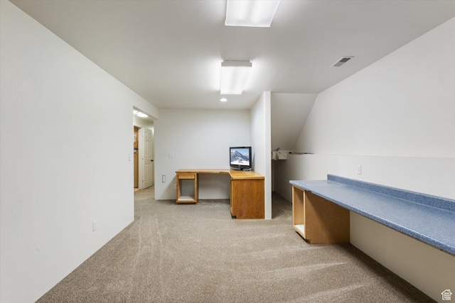 home office with built in study area, visible vents, and light colored carpet