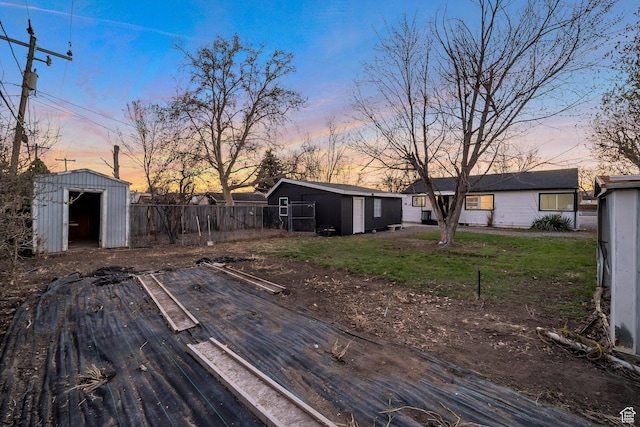 view of yard featuring an outbuilding, fence, and a storage shed