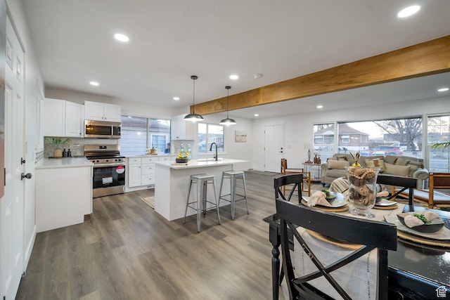 kitchen featuring decorative backsplash, open floor plan, dark wood-style floors, and appliances with stainless steel finishes