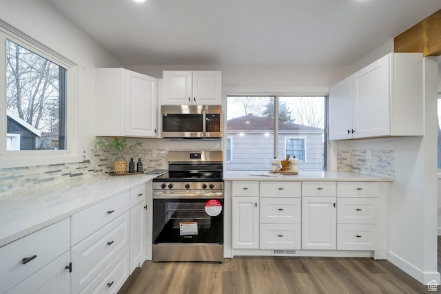 kitchen featuring light countertops, white cabinets, wood finished floors, stainless steel appliances, and tasteful backsplash