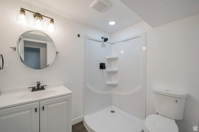 bathroom with toilet, vanity, walk in shower, baseboards, and visible vents
