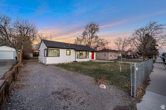 view of front facade with an outbuilding, fence, gravel driveway, a lawn, and a garage