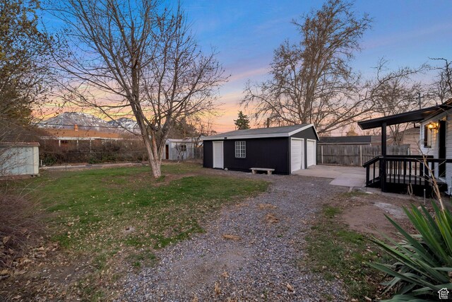 yard at dusk featuring fence and an outdoor structure