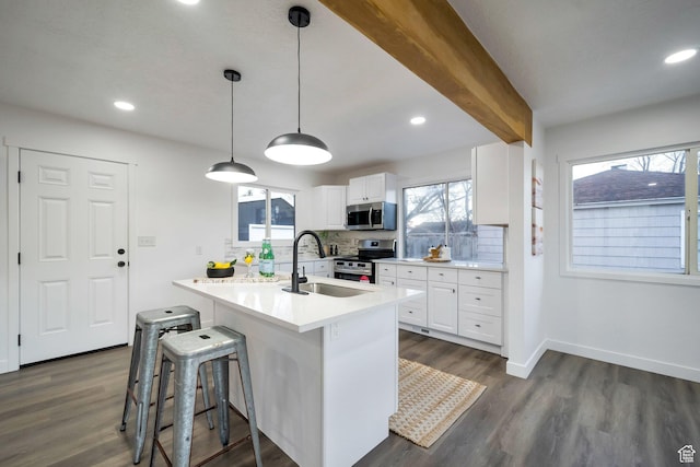 kitchen with a sink, stainless steel appliances, tasteful backsplash, and dark wood finished floors