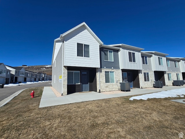 526 N Richland Valley St Unit 10, Garden City, UT 84028 - view of front of house featuring stone siding, a residential view, a front yard, and central air condition unit