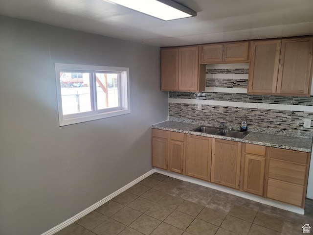 250 8th St, Wendover, UT 84083 - kitchen featuring dark tile patterned floors, baseboards, backsplash, a sink, and light stone counters