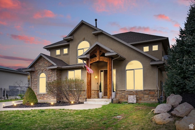 view of front of home featuring stone siding, a front yard, and stucco siding
