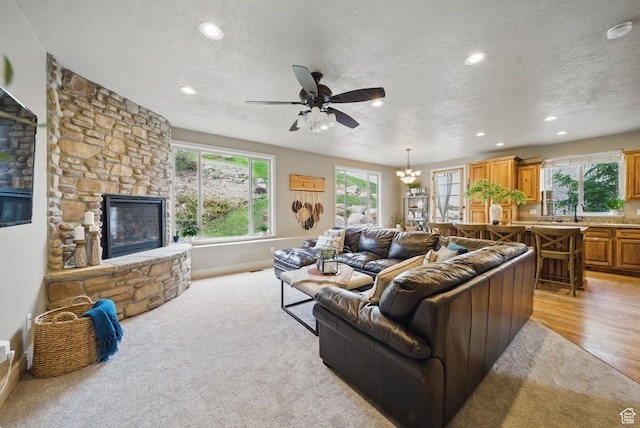 1637 E 2400 N, Layton, UT 84040 - living area featuring a textured ceiling, ceiling fan with notable chandelier, a fireplace, and a wealth of natural light