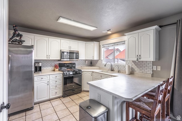 1301 W Indian Hills Dr Unit 59, St George, UT 84770 - kitchen featuring a sink, a kitchen breakfast bar, a peninsula, stainless steel appliances, and visible vents