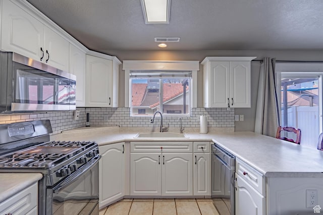 1301 W Indian Hills Dr Unit 59, St George, UT 84770 - kitchen featuring light tile patterned floors, stainless steel appliances, a sink, white cabinets, and a peninsula