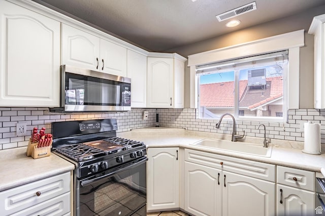 1301 W Indian Hills Dr Unit 59, St George, UT 84770 - kitchen with a sink, stainless steel microwave, black gas stove, visible vents, and white cabinets
