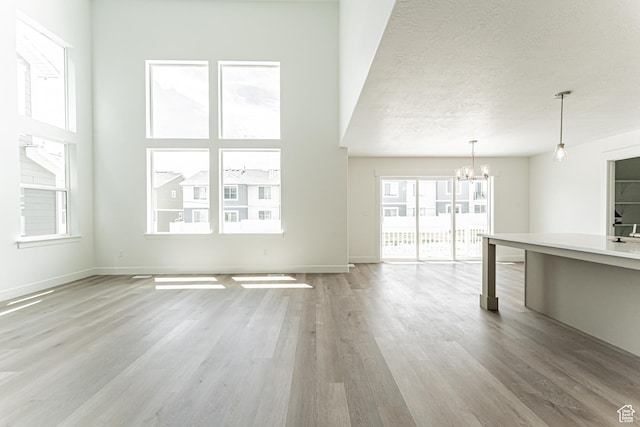 3877 W 950 N Unit 367, Lehi, UT 84043 - unfurnished living room featuring a chandelier, light wood-style flooring, and a textured ceiling