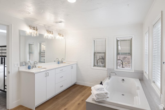199 N 300 W, Garden City, UT 84028 - bathroom with a sink, a garden tub, visible vents, double vanity, and wood finished floors