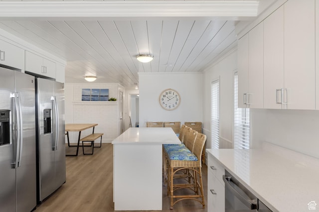 199 N 300 W, Garden City, UT 84028 - kitchen with light countertops, light wood-style flooring, ornamental molding, appliances with stainless steel finishes, and a breakfast bar area