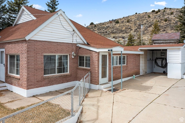 view of front of property featuring entry steps, a shingled roof, fence, and brick siding