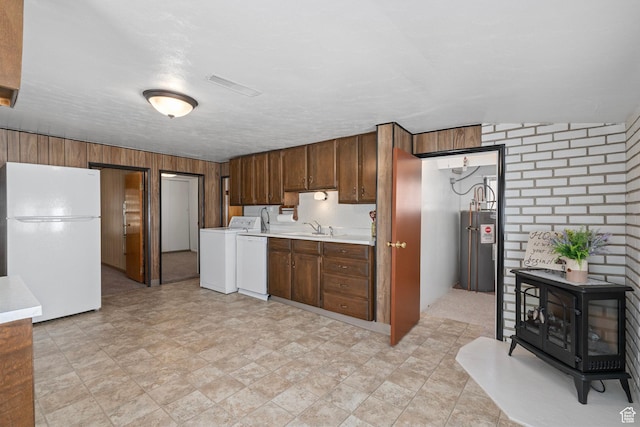 kitchen with water heater, light countertops, washer / clothes dryer, a sink, and freestanding refrigerator
