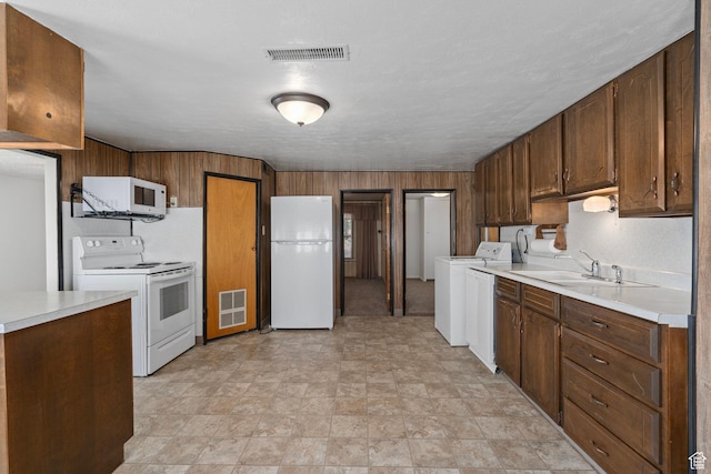 kitchen featuring light countertops, visible vents, white appliances, washer / clothes dryer, and a sink