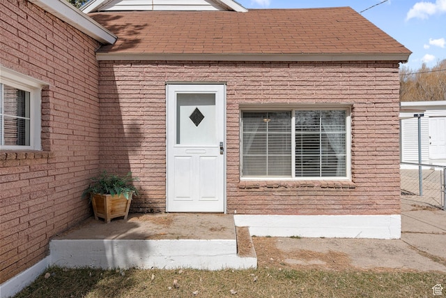 property entrance with brick siding and roof with shingles