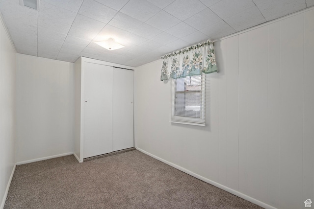 unfurnished bedroom featuring a closet, carpet flooring, visible vents, and baseboards