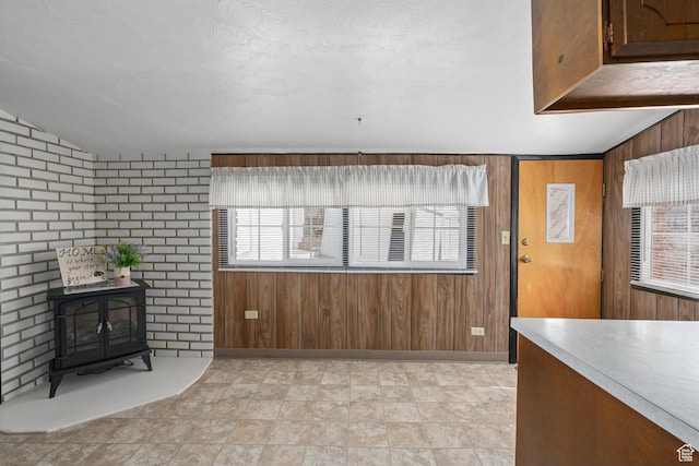 unfurnished living room featuring lofted ceiling, wooden walls, and a wood stove