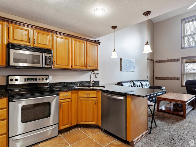 3615 N Wolf Lodge Dr E Unit 109, Eden, UT 84310 - kitchen featuring light tile patterned flooring, a peninsula, stainless steel appliances, a sink, and pendant lighting