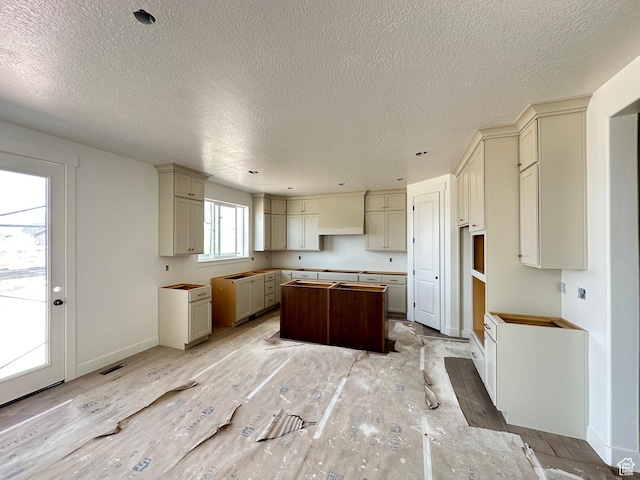 261 E 1150 N Unit 72, Salem, UT 84653 - kitchen featuring a kitchen island, a textured ceiling, cream cabinets, and baseboards