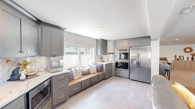 452 S 2500 E Unit 122, Spanish Fork, UT 84660 - kitchen featuring stainless steel appliances, gray cabinetry, a textured ceiling, light stone counters, and visible vents