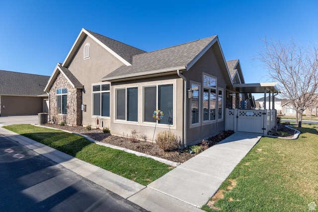 view of front of home with a front yard, a gate, stone siding, stucco siding, and a shingled roof