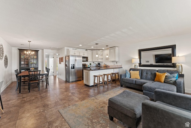 living area with baseboards, recessed lighting, a notable chandelier, and a textured ceiling
