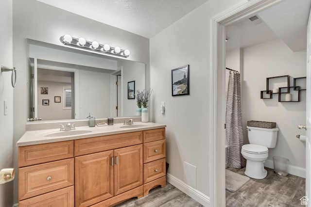 bathroom featuring toilet, a sink, double vanity, and wood finished floors