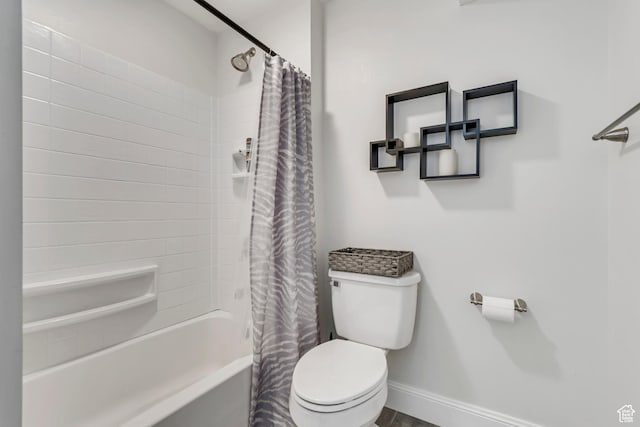 bathroom with toilet, baseboards, and shower / tub combo