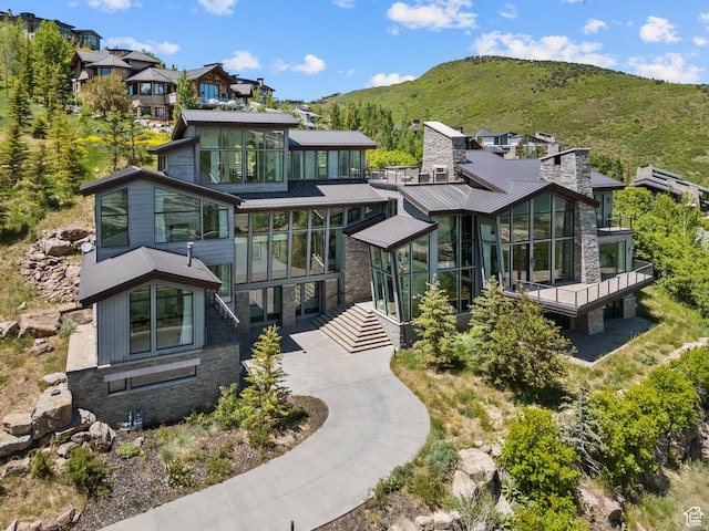 2908 W Deer Pointe Dr, Heber City, UT 84032 - view of front of property featuring a sunroom, stone siding, a mountain view, a metal roof, and a standing seam roof