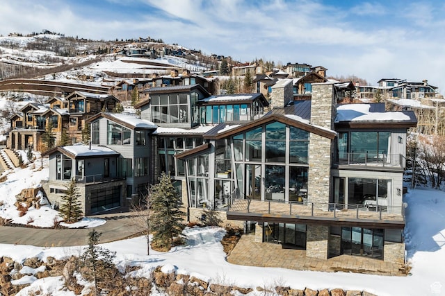 2908 W Deer Pointe Dr, Heber City, UT 84032 - snow covered property featuring a residential view, a chimney, a sunroom, and stone siding