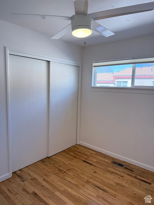 650 N 300 W Unit 234, Salt Lake City, UT 84103 - unfurnished bedroom with a closet, light wood finished floors, baseboards, visible vents, and ceiling fan