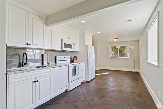 kitchen with white cabinetry, white appliances, baseboards, backsplash, and a sink