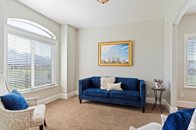 living area with carpet flooring, arched walkways, and a healthy amount of sunlight