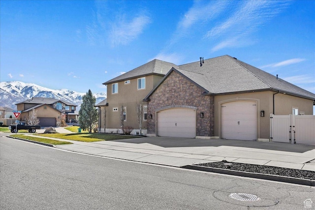 view of front of home featuring stucco siding, fence, an attached garage, driveway, and a mountain view