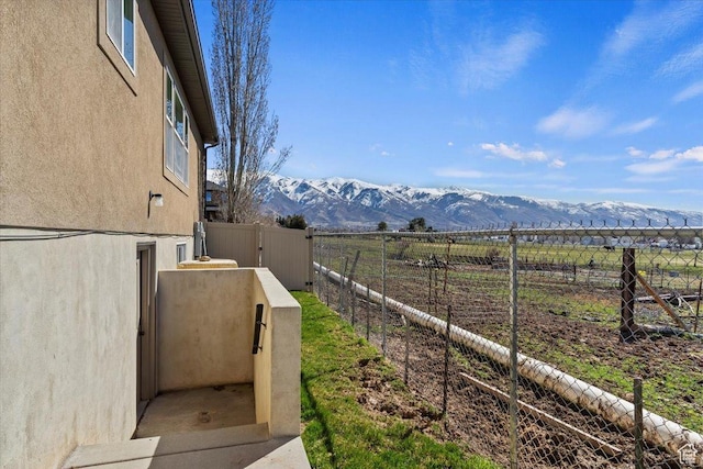 view of yard featuring a mountain view, a rural view, and fence