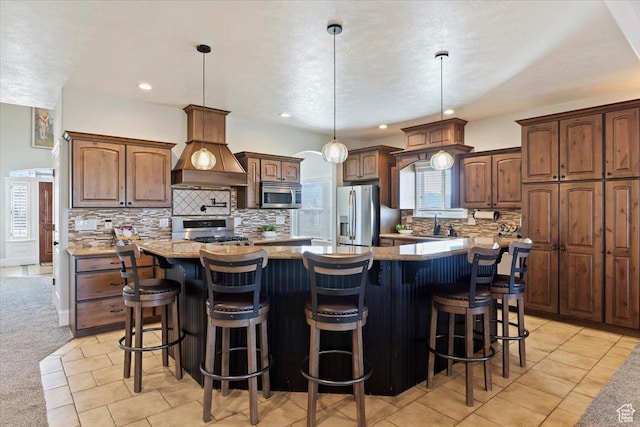 kitchen featuring tasteful backsplash, appliances with stainless steel finishes, a spacious island, and custom exhaust hood
